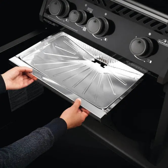 Person removing a Napoleon grill drip tray from a black outdoor BBQ grill.