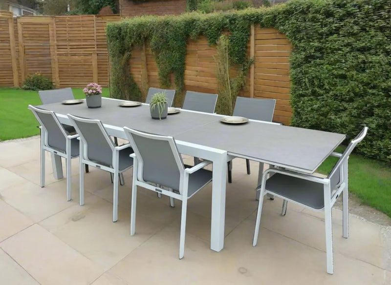 Outdoor patio set with a large dining table and chairs on a paved area.